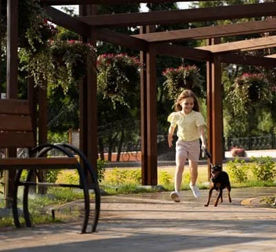 A child walking her dog beneath a garden pergola